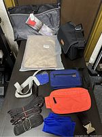 Photo shows assortment of travel bags, straps, and the new non-slip bath mat still in packaging on a flat surface.