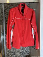 Front view of red women's coat showing zipper closure, white side panels, and white piping detailing