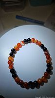 Natural red agate and jet black onyx stretchy bracelet laid flat showing bead arrangement.