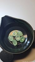 Seven oval mint green kyanite cabochon gemstones with visible natural inclusions in a black container.