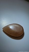 Pear-shaped natural peach moonstone cabochon showing peach color and internal shimmer under light.
