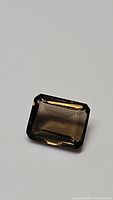 Close-up photo of the 3.07 carat natural emerald cut Smokey Quartz gemstone showing its color, cut, and clarity.