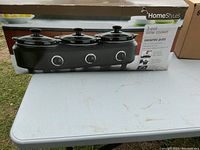 Image showing the product box featuring the HomeStyles 3-pot slow cooker with ceramic pots, the box is slightly damaged.