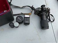 Full lot view showing Yashica SR-45 camera with zoom lens attached, battery tester flash unit, lens cap, small accessory cylinder, and leather carrying case.