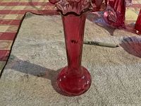 Full side view of cranberry glass vase showing bulbous base and fluted neck.