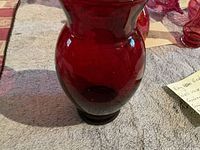 Front view of deep ruby red glass vase on a towel.