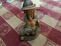 Single figurine showing a boy with rabbit and birds sitting on a base, wearing a hat and traditional clothing.