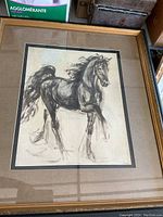 Framed black and white horse painting under glass in a gold-tone frame.