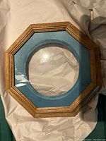 Wooden octagonal frame with blue fabric insert, circular cutout for plate display.
