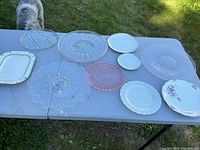 All platters and plates on a white folding table outdoors.
