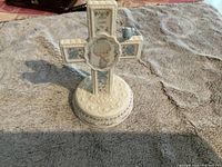 Front view of Jesus Loves Me cross figurine with bird decoration and floral pattern.