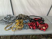 Photo showing assorted ropes and ratchet straps on a table, various colors and types present