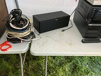 Yamaha center speaker and bundle of assorted cables next to table holding main audio components.