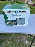 Photo of closed box packaging showing brand H2OT Water Now portable water heater with product image and usage details.
