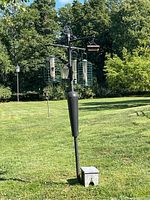 Full view of the bird feeding station with feeders hanging and small step stool in foreground on green grass lawn.
