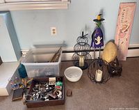 Assorted lot on floor including jewelry tray, plastic box, decorative items, candle holders, and figurines.