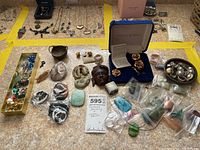 Full overview of the jewelry lot on countertop showing necklaces, earrings, loose stones, brooches, and pins.