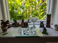 Wide angle showing all figurines arranged on a windowsill with natural light highlighting various materials and colors.