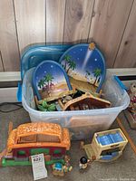 Overall view of plastic container holding the Fisher Price Nativity set including roof pieces, scenic backdrops, figurines, and other components.
