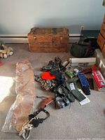 Overview of hunting gear laid on carpet with wooden trunks in background