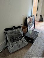 Overview of the lot items including poker chip case, basket, Miller Genuine Draft mirror, Chivas Regal wall clock, all placed on carpeted floor against wall.