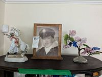 View of all three items: signed photo in wooden frame, porcelain horse trainer figure, glass and porcelain flower tree.