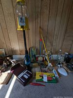 Wide view of the vintage toy collection showing gumball machine, pushers, board games, and other toys on the floor against wood panel wall.