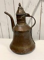 Front angle view showing the dallah's spout, handle, and domed hinged lid with finial.