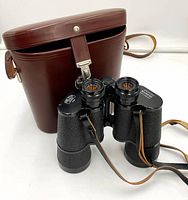 Front view of binoculars with closed brown leather case behind