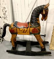 Full side view of the carved wood rocking horse displaying the original stained paint and black rockers.