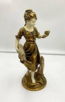Front view of Emile Bruchon signed spelter maid statue painted in gold and ivory colors, showing full figure, base, and details.