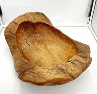 Front view showing the carved shallow interior and rough natural edges of the wooden scoop bowl.
