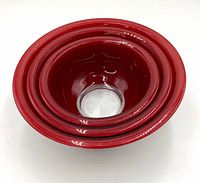 Top-down view of the three red Pyrex nesting bowls stacked inside each other, clear glass bottom visible.