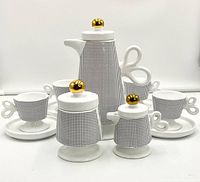 Full set photographed including espresso pot, lidded sugar bowl, creamer, 4 cups and 4 saucers arranged in front, showing all items in set.