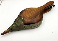 Wood and suede bellows viewed from top angle showing polished wood surface, suede section, and copper tip with brass rivet details.