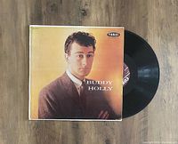 Album cover featuring Buddy Holly portrait with Coral Records logo and visible black vinyl record with label.