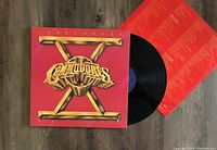 Vinyl LP record in original cover with visible black vinyl disc and red lyric insert sheet.