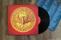 Red and orange album cover with gold emblem, black vinyl record with red center label, and blue inner sleeve with printed text visible.