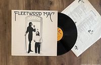 Photo of Fleetwood Mac self-titled vinyl LP record with printed inner sleeve and album cover showing two men, one standing and one seated, black and white photo.