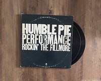 Top-down image of the Humble Pie 'Rockin' The Fillmore' LP vinyl record cover and partially visible vinyl record on a wooden surface.