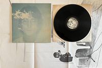 Contents of the lot including the vinyl record partially out of its inner sleeve, the album cover, and the black and white poster.