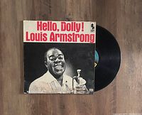 Black vinyl LP record with sleeve featuring Louis Armstrong smiling and holding a trumpet, titled 'Hello, Dolly!' in red and black text.