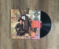 Vinyl record and cover of 'More Gunfighter Ballads and Trail Songs' by Marty Robbins showing front cover with artist posing in Western attire and promotional sticker on the cover.