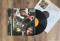Neil Young & Crazy Horse American Stars N' Bars vinyl LP partially out of sleeve, showing cover art and vinyl disc with yellow label, with lyric inner sleeve behind.