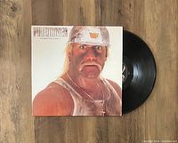 Vinyl LP record and album cover showing the front cover with wrestler wearing white hard hat and the black record partially outside the sleeve.