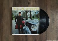 Photo of vinyl album cover 'The Classic Roy Orbison' showing Roy Orbison standing next to a vintage car with two vinyl records partially visible behind the cover.