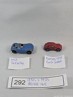 Two small vintage diecast cars: red 1939 Barclay Buick Sedan and blue 1950 Tootsietoy Chevrolet Chevy, with handwritten labels.