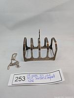 Vintage silver toast rack with hallmarks and broken necklace beside it.