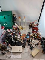 Photo of entire Christmas village and decorations lot showing light-up buildings, candles, figurines, and lighting cords.