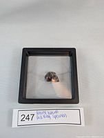 Front view of the natural red ruby specimen displayed in a black frame under clear lighting.